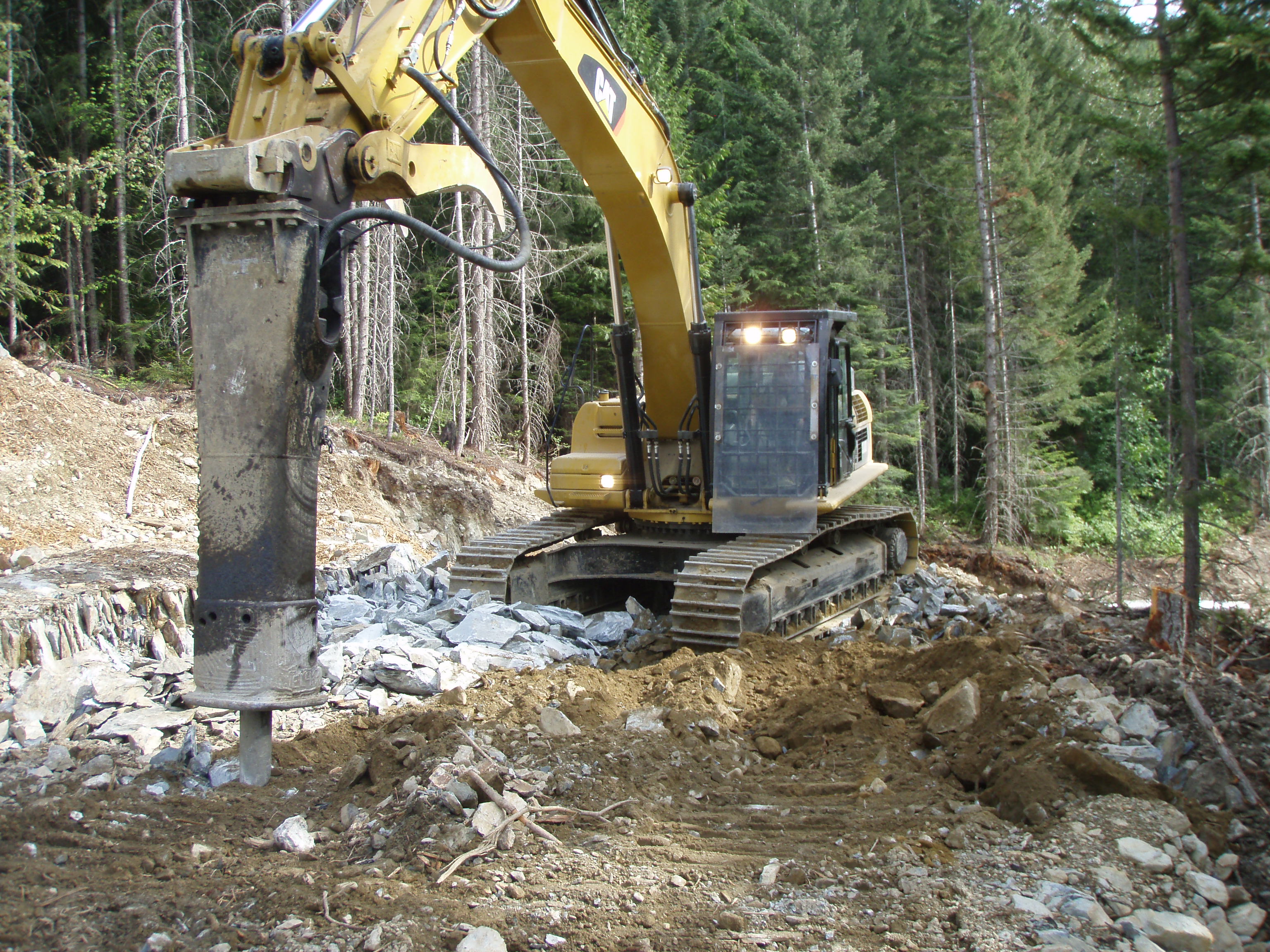CAT excavator with rock hammer hydro access road construction forest