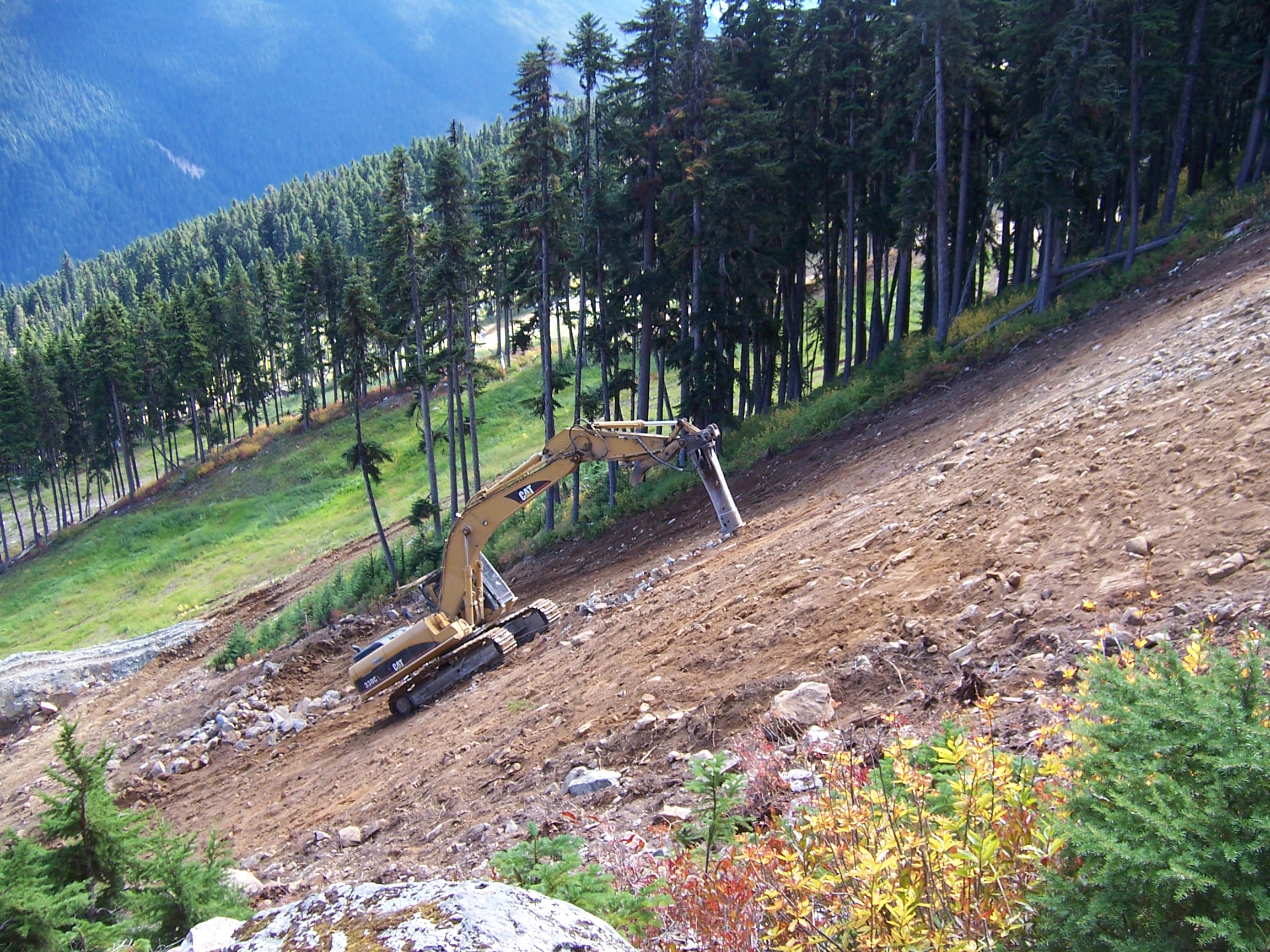 CAT excavator cutting ski trail alpine slope Whistler