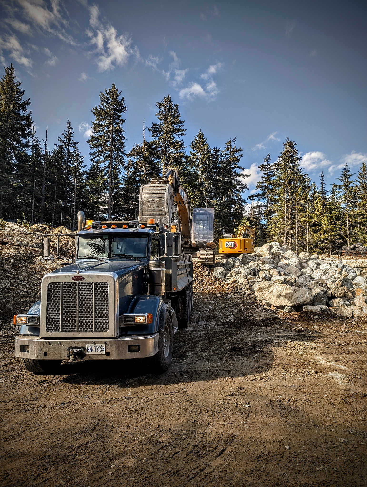 Peterbilt dump truck and CAT excavator on site Sea to Sky Corridor